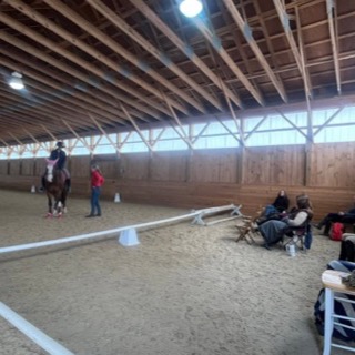 Felicitas talking with a rider while auditors watch from chairs along the wall